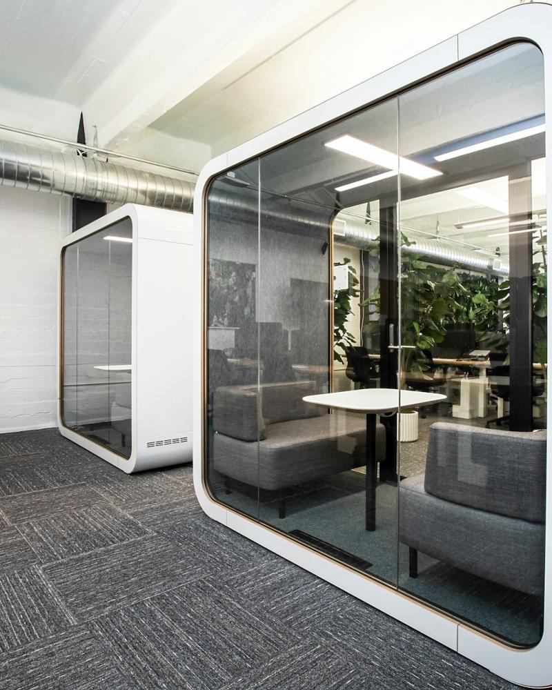 A sleek, modern office with private soundproof meeting pods, representing flexible workspace solutions.