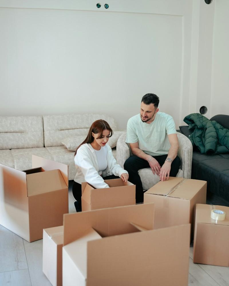 A couple packing boxes in their living room, preparing for a smooth transition to their new home.