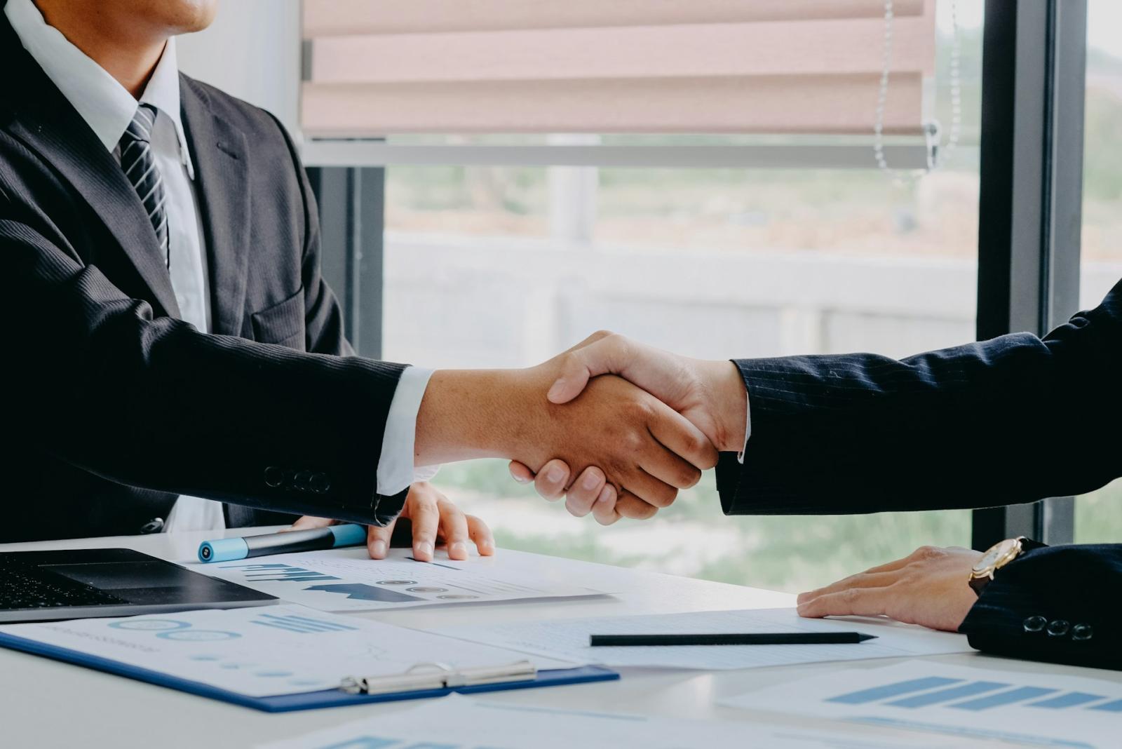 Two professionals shaking hands in a corporate office setting, finalizing a lease negotiation.